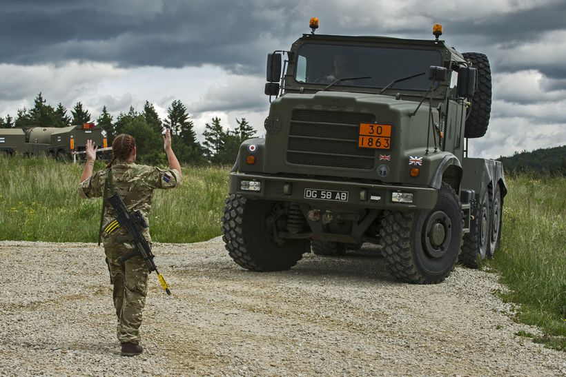 Female soldier guides military truck