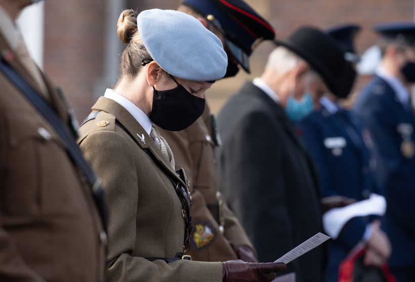 A female soldier wearing beret looks at order of service