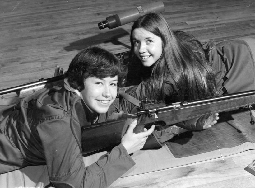 Jean and her sister Jo lie down holding rifles in the Army