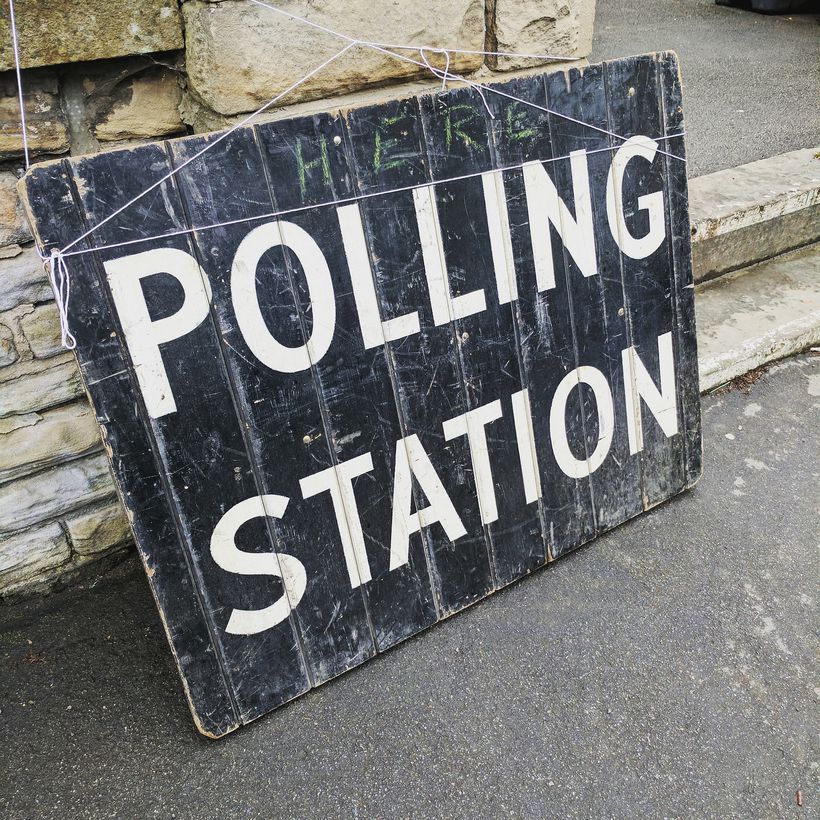 Black wooden sign with Polling Station written in white paint