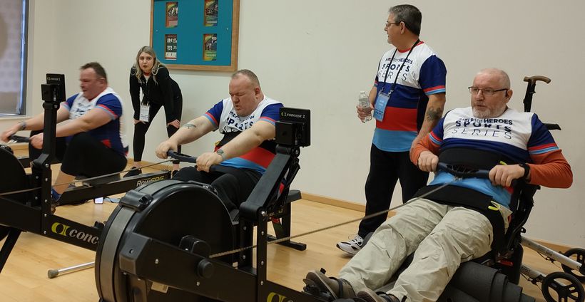 Martin, right, competes in a rowing race with other veterans cheered on by supporters. - Credit: Help for Heroes. Veterans taking part in an indoor rowing race.